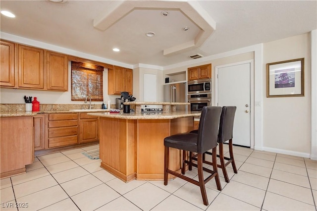 kitchen with sink, a breakfast bar area, a center island, light tile patterned floors, and appliances with stainless steel finishes