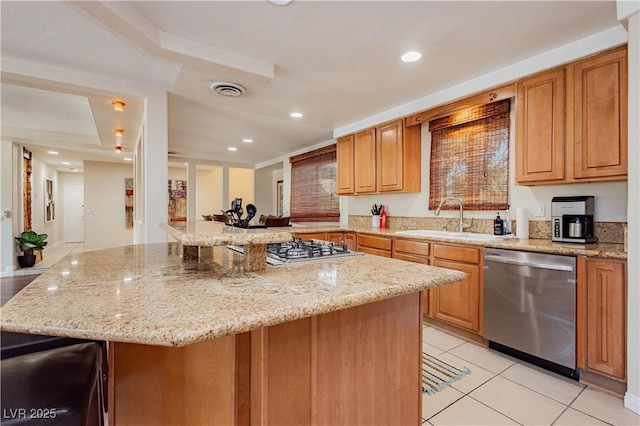 kitchen featuring appliances with stainless steel finishes, light stone countertops, sink, and a breakfast bar area