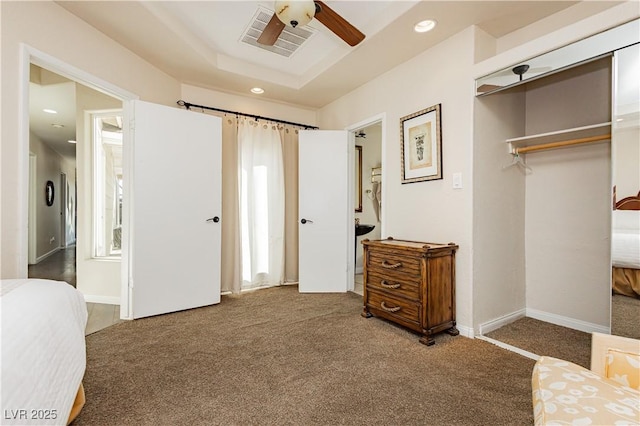 bedroom with a raised ceiling, carpet flooring, ceiling fan, and a closet