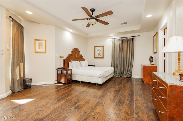 bedroom with dark wood-type flooring and a raised ceiling