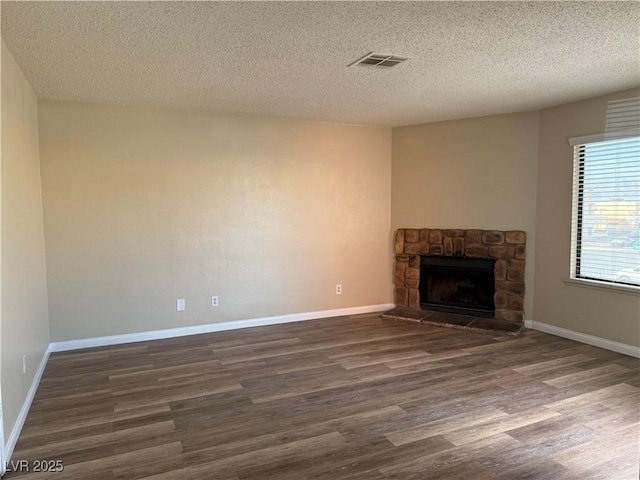 unfurnished living room featuring dark wood-type flooring, a textured ceiling, and a fireplace