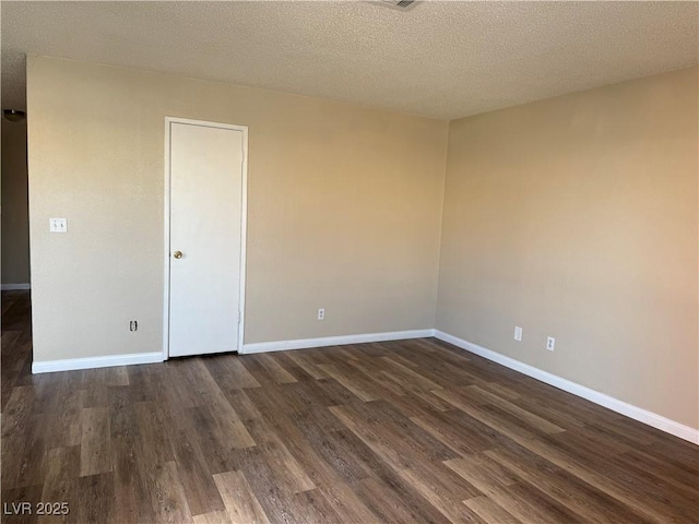 empty room with dark hardwood / wood-style flooring and a textured ceiling