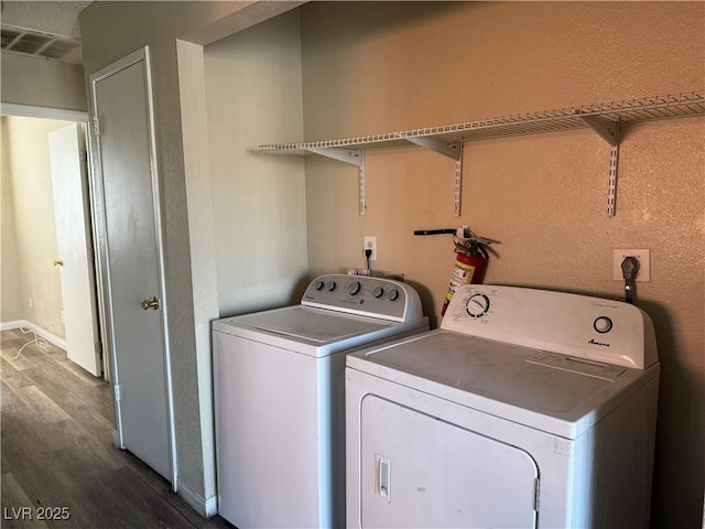 clothes washing area with dark hardwood / wood-style flooring and independent washer and dryer