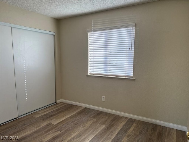 unfurnished bedroom featuring hardwood / wood-style floors, a textured ceiling, and a closet