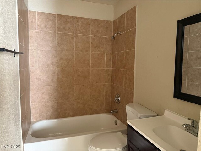 full bathroom with tiled shower / bath, vanity, and toilet