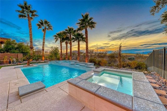 pool at dusk with an in ground hot tub and a patio