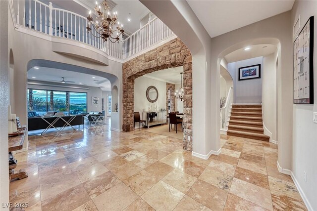 foyer featuring a towering ceiling and ceiling fan with notable chandelier