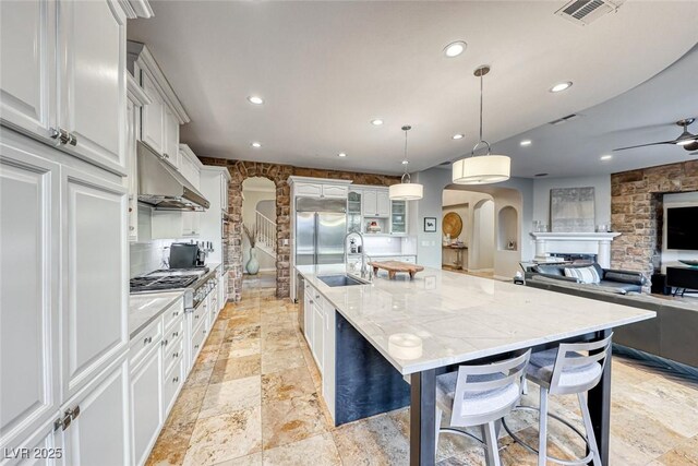 kitchen featuring a large island, sink, white cabinetry, hanging light fixtures, and stainless steel appliances