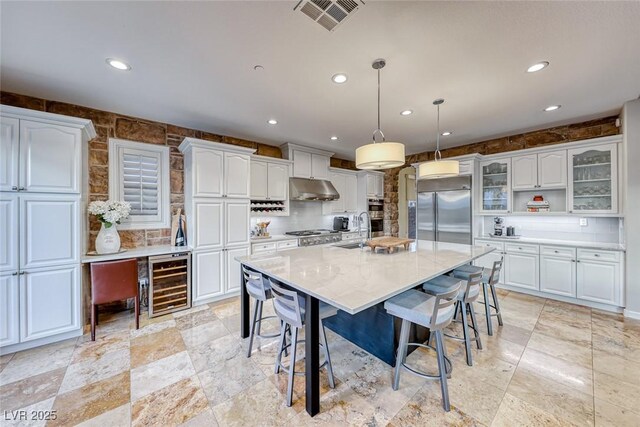 kitchen with a kitchen island, pendant lighting, white cabinets, wine cooler, and built in refrigerator