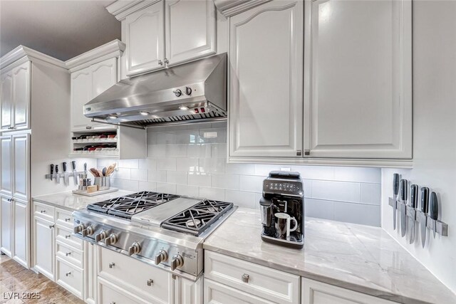 kitchen with stainless steel gas stovetop, white cabinetry, light stone countertops, and decorative backsplash