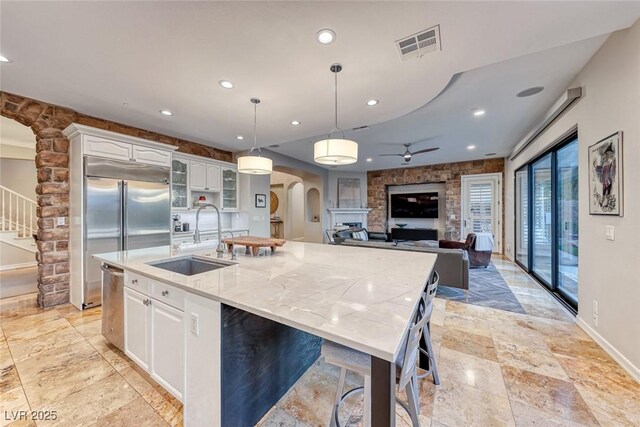 kitchen with a large island, sink, white cabinetry, and decorative light fixtures