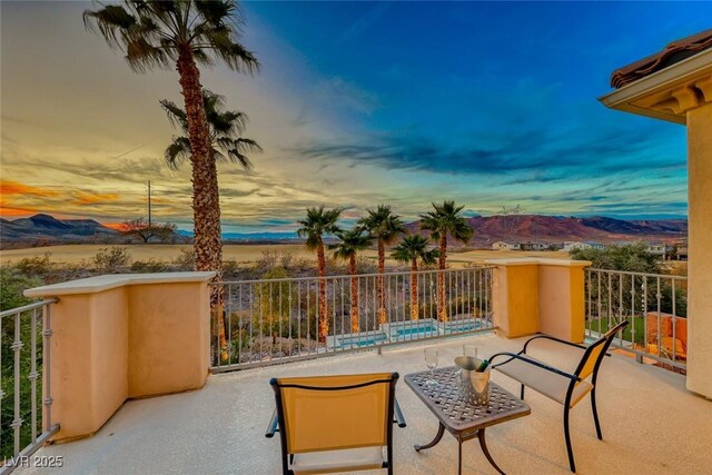 patio terrace at dusk featuring a mountain view and a balcony