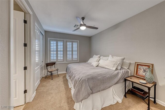 bedroom with light colored carpet, ceiling fan, and a closet