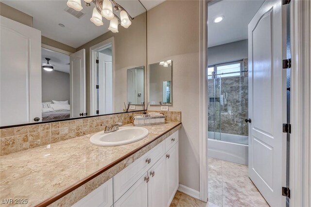 bathroom with tasteful backsplash, vanity, and bath / shower combo with glass door