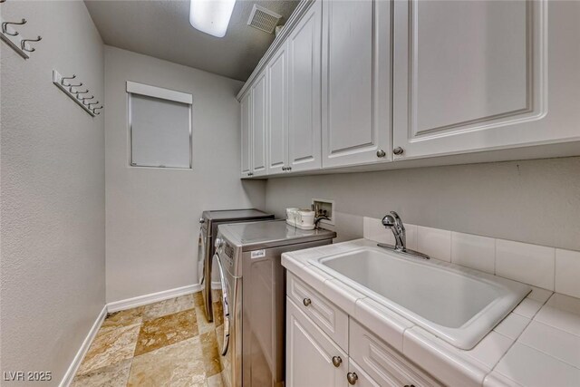 clothes washing area with sink, cabinets, and washer and dryer