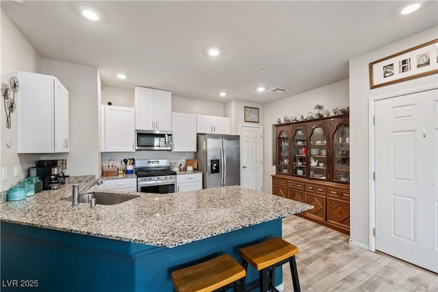 kitchen with light stone counters, stainless steel appliances, a breakfast bar, and sink