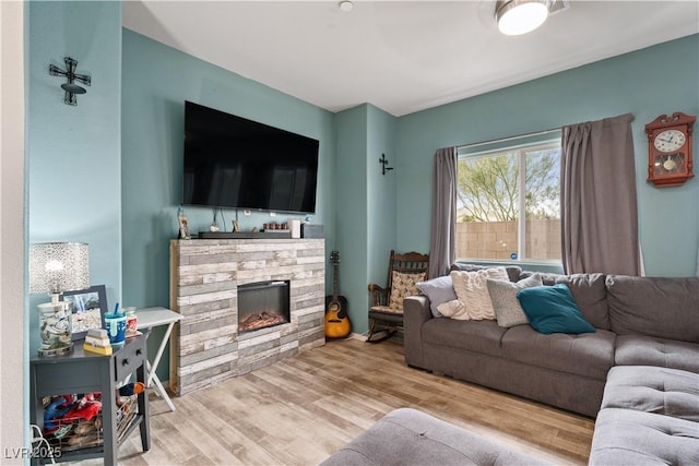 living room featuring wood-type flooring and a stone fireplace