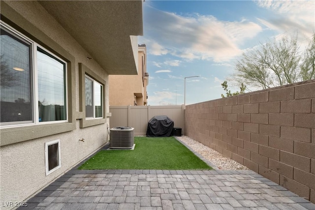 view of yard with central AC and a patio