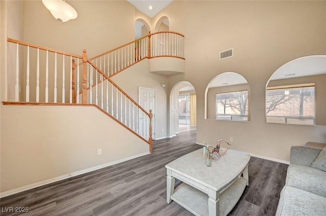 unfurnished living room with a towering ceiling and dark hardwood / wood-style flooring