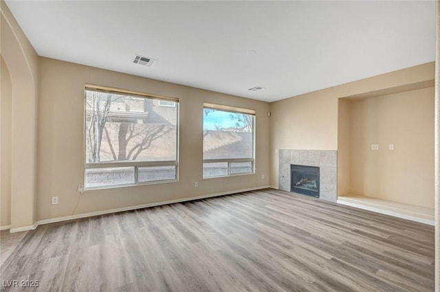 unfurnished living room with a tile fireplace and light hardwood / wood-style flooring