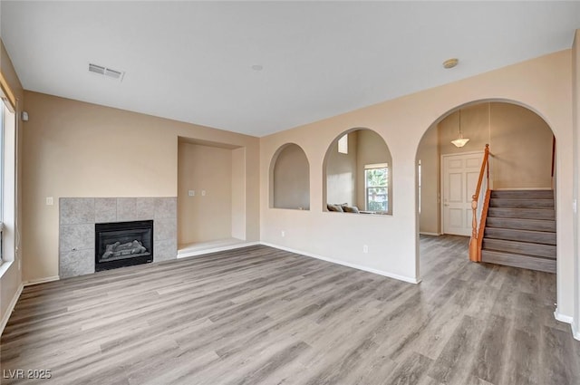 unfurnished living room featuring a tiled fireplace and light hardwood / wood-style floors