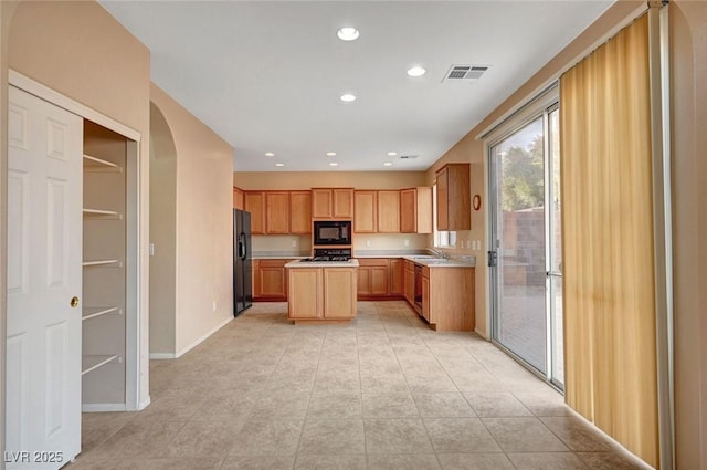 kitchen featuring a kitchen island, sink, light tile patterned floors, and black appliances