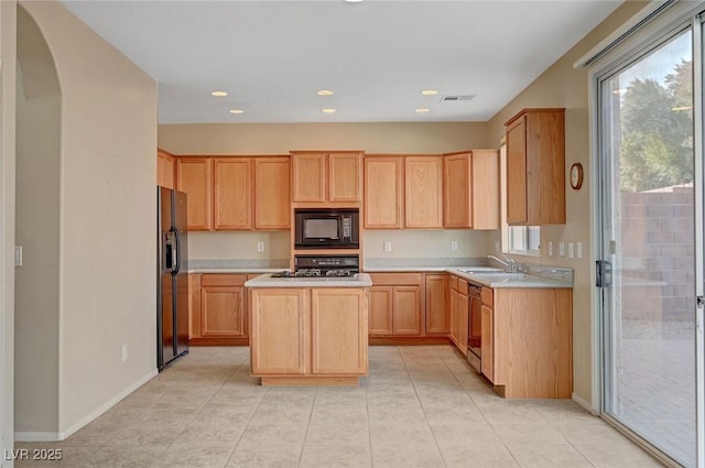 kitchen featuring light tile patterned flooring, sink, a center island, black appliances, and light brown cabinets