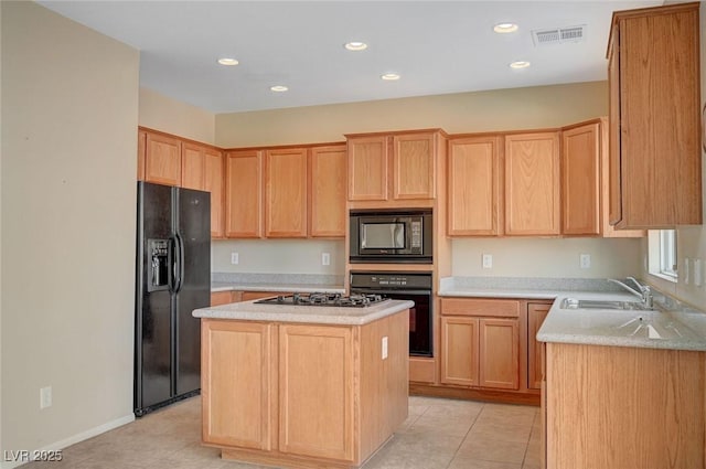 kitchen with sink, a center island, black appliances, light tile patterned flooring, and light brown cabinetry