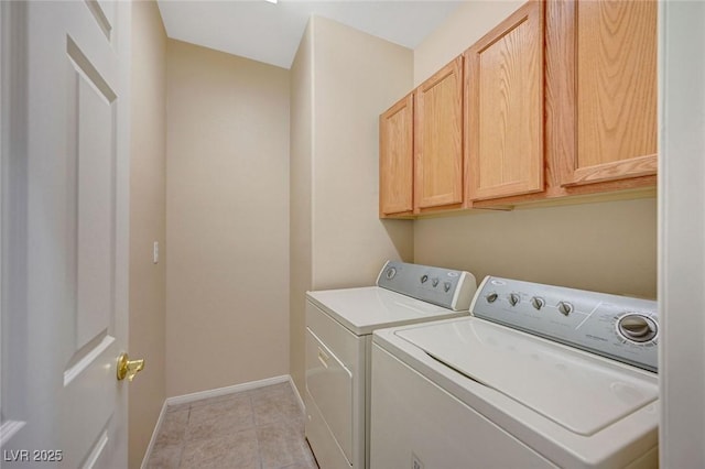 washroom with light tile patterned floors, washing machine and dryer, and cabinets