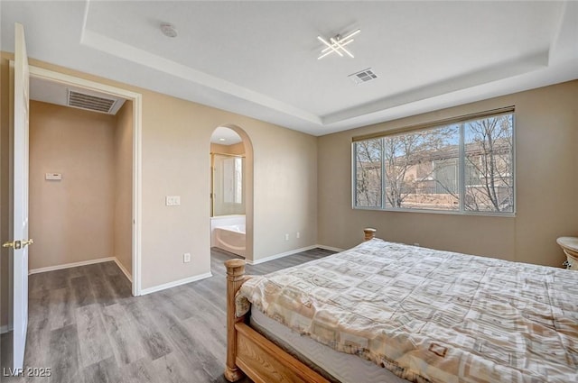 bedroom with hardwood / wood-style flooring and a tray ceiling