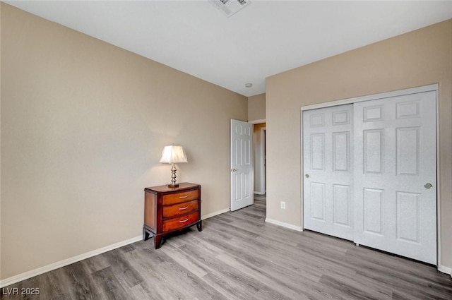 bedroom with light hardwood / wood-style floors and a closet