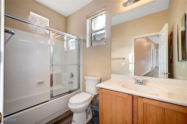 full bathroom featuring vanity, hardwood / wood-style floors, bath / shower combo with glass door, and toilet