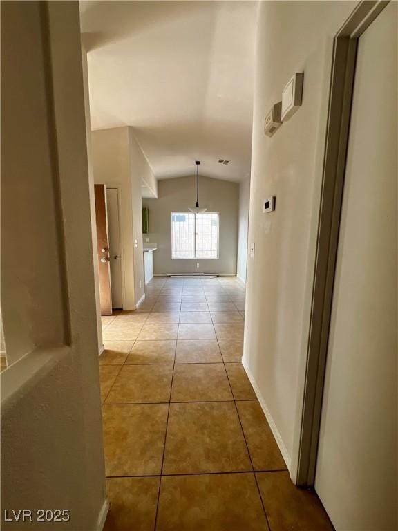 hall featuring lofted ceiling and light tile patterned floors