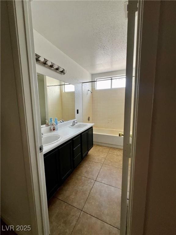 bathroom with vanity, tiled shower / bath, tile patterned floors, and a textured ceiling