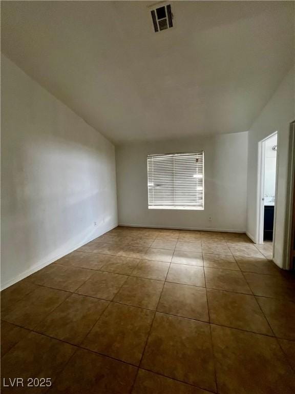 tiled spare room featuring vaulted ceiling