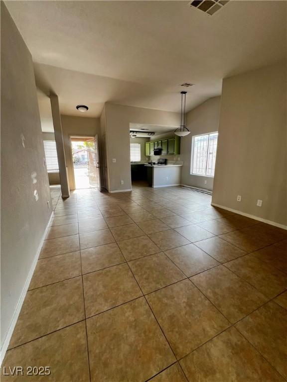 unfurnished living room with vaulted ceiling and tile patterned floors