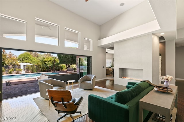 living room with a towering ceiling, hardwood / wood-style floors, and a tile fireplace