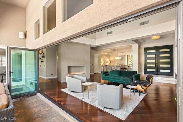 interior space featuring a high ceiling, a large fireplace, dark hardwood / wood-style floors, and french doors