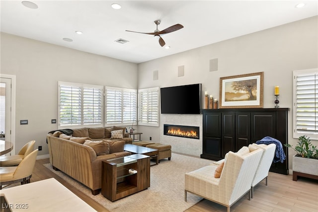 living room with plenty of natural light, ceiling fan, and light wood-type flooring