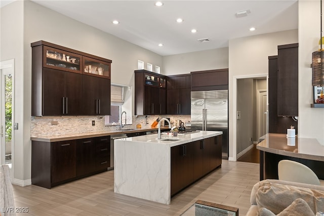 kitchen featuring stainless steel appliances, an island with sink, sink, and backsplash