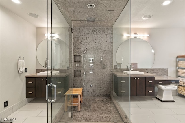 bathroom with a shower with door, vanity, and tile patterned floors