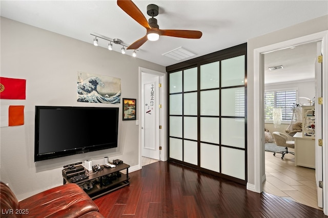 living room featuring dark wood-type flooring, track lighting, and ceiling fan