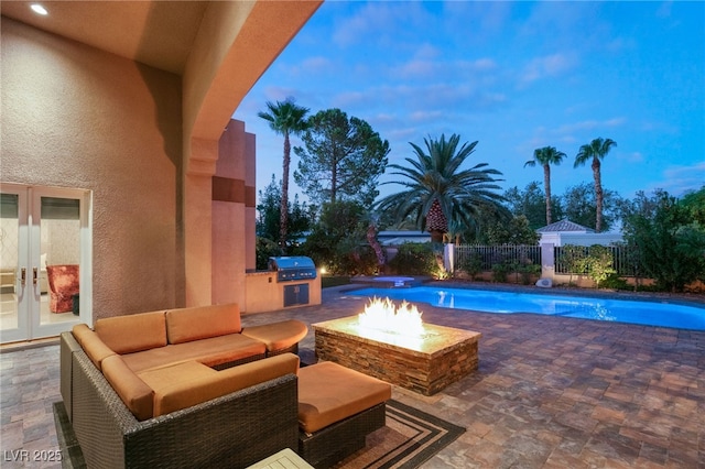 pool at dusk featuring french doors, a patio, grilling area, and an outdoor fire pit