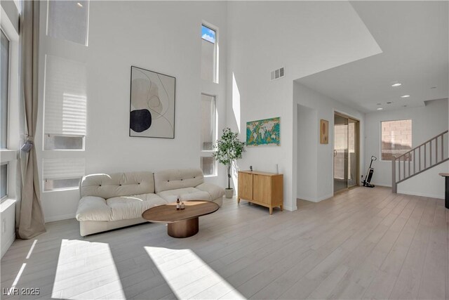 living room with plenty of natural light, light hardwood / wood-style floors, and a high ceiling