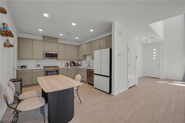 kitchen featuring sink, gray cabinetry, stainless steel appliances, a kitchen breakfast bar, and light wood-type flooring