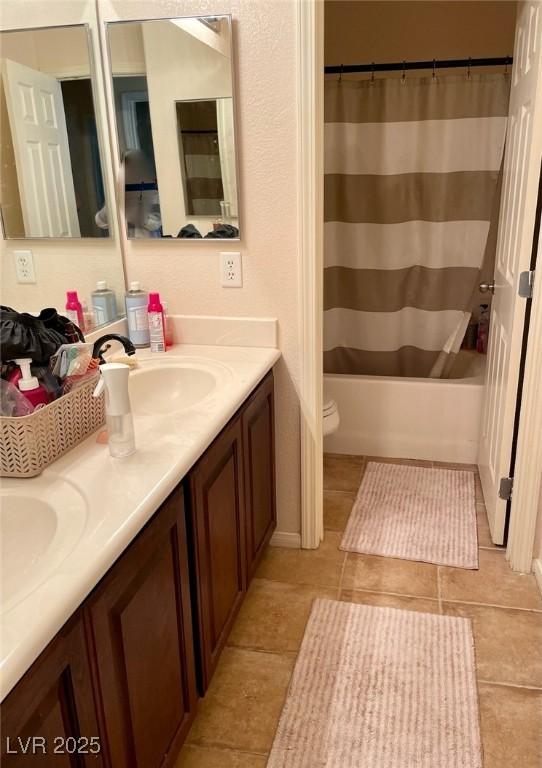 full bath with double vanity, shower / bath combo, a sink, and toilet