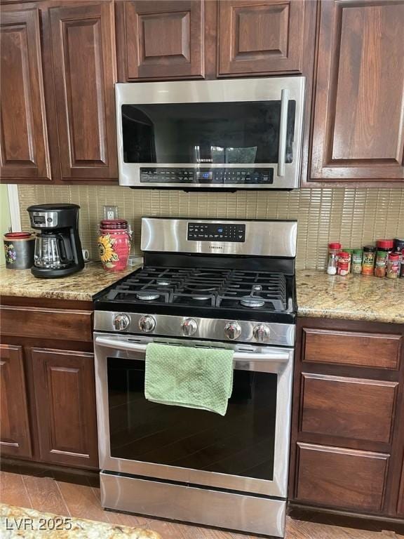 kitchen with appliances with stainless steel finishes, decorative backsplash, and light stone countertops