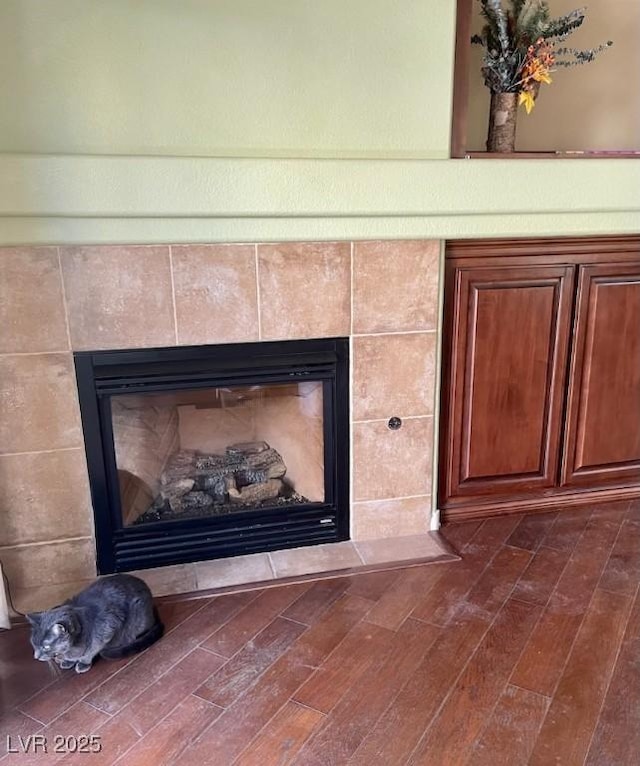 details featuring a tiled fireplace and wood finished floors