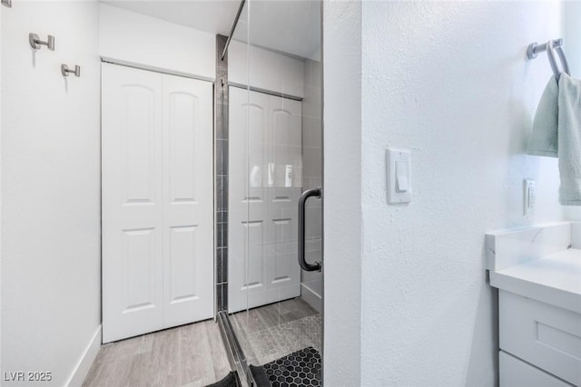 bathroom with hardwood / wood-style flooring and a shower with shower door