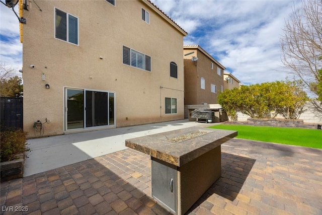 rear view of house featuring a fire pit and a patio